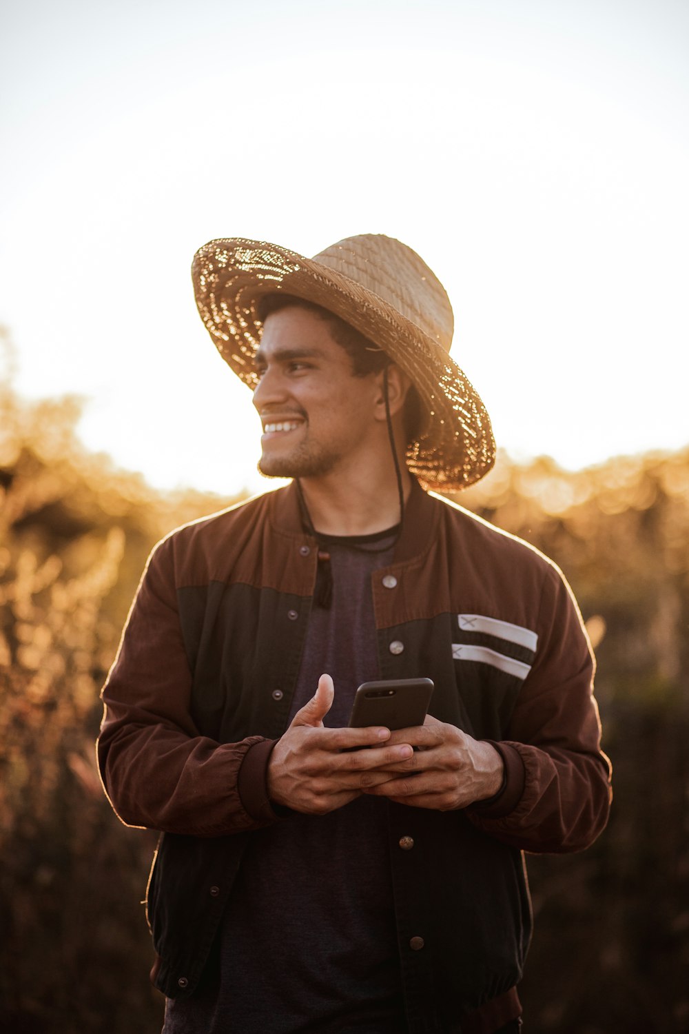 Homme au chapeau brun tenant un smartphone noir