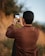 man in brown long sleeve shirt taking photo of sunset