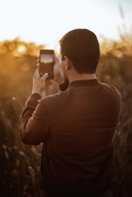 man in gray long sleeve shirt holding black smartphone