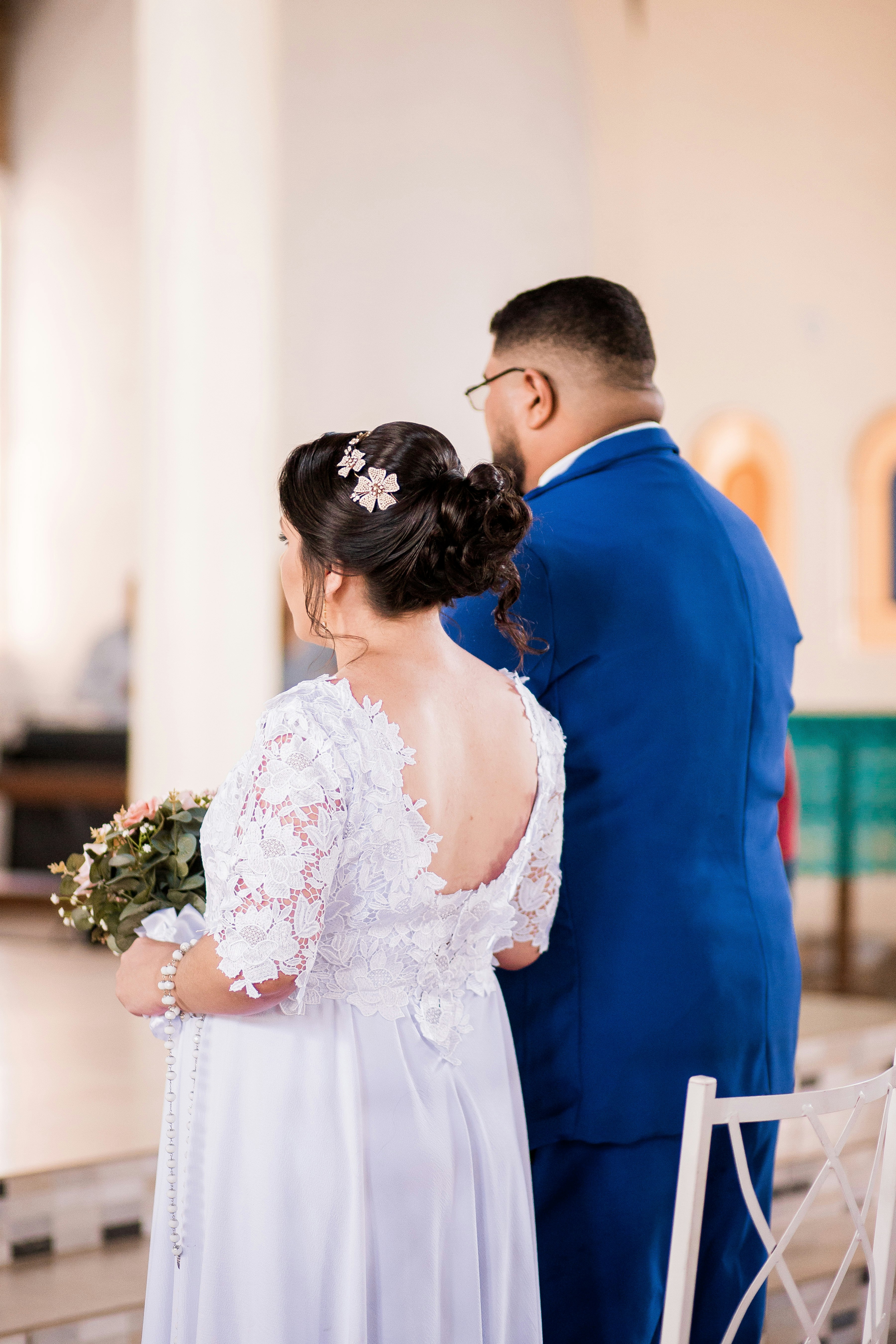 man in blue suit and woman in white floral wedding dress kissing