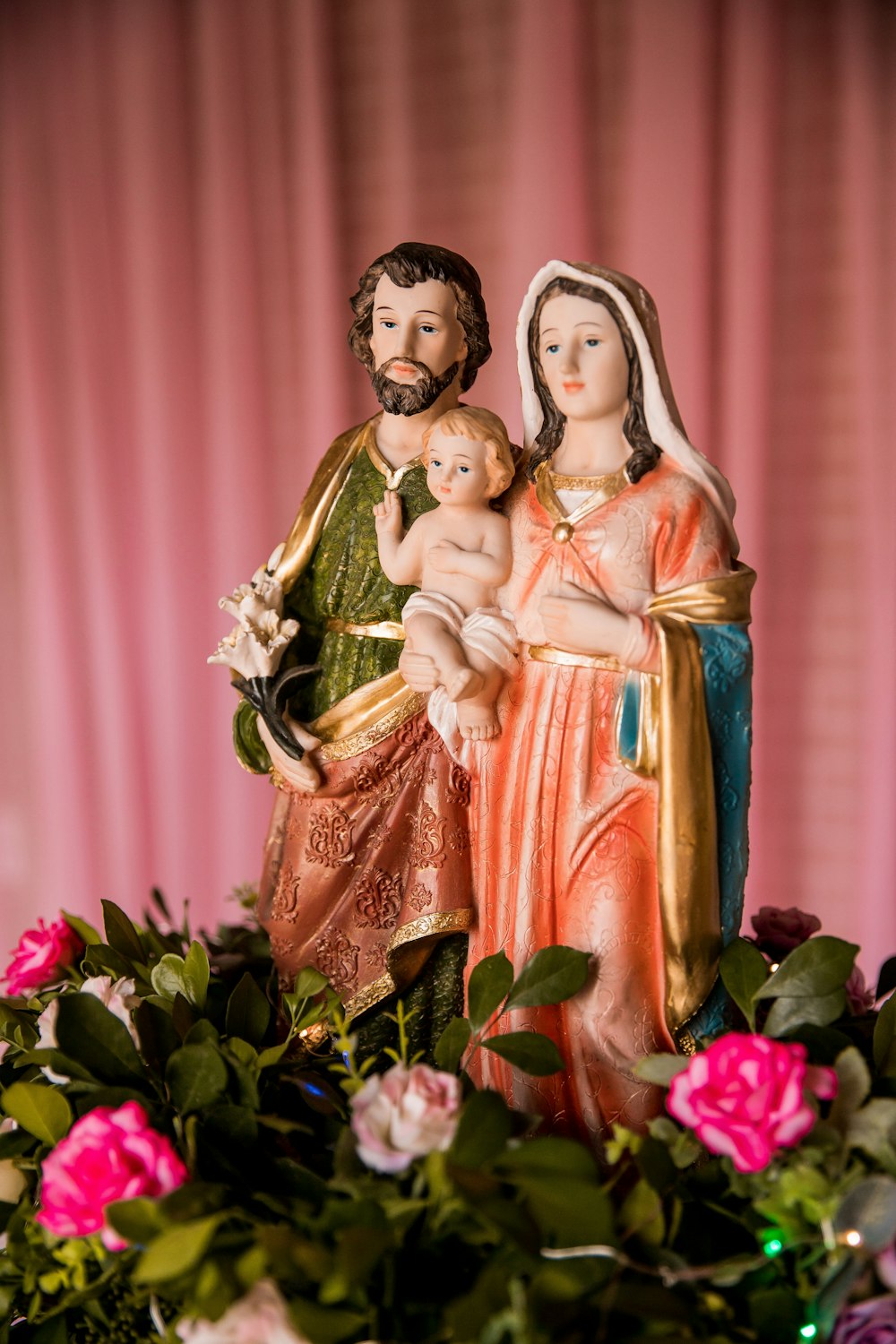 Statuetta della Vergine Maria su tessuto floreale rosso e verde
