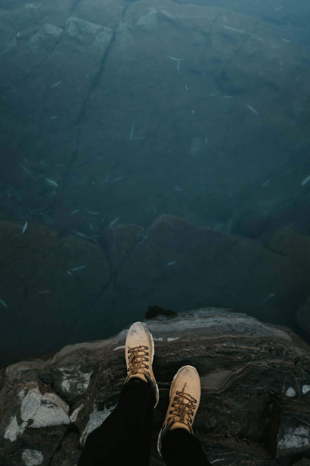 Persona con zapatos marrones de pie en un suelo rocoso