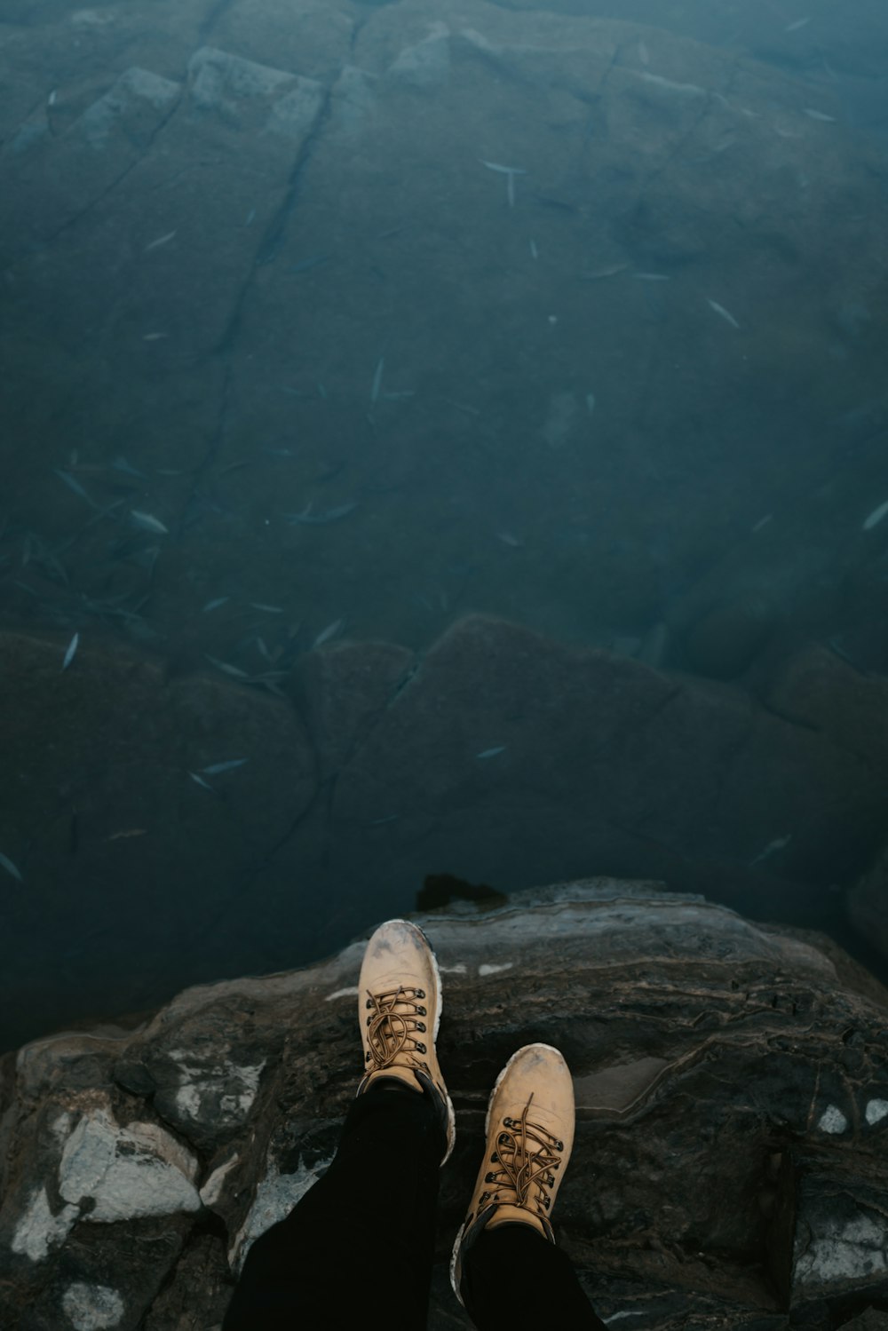 person in brown shoes standing on rocky ground