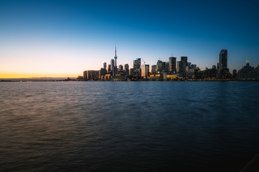 city skyline across body of water during sunset