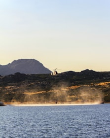 A helicopter hovering above lush green hills with a river winding below.