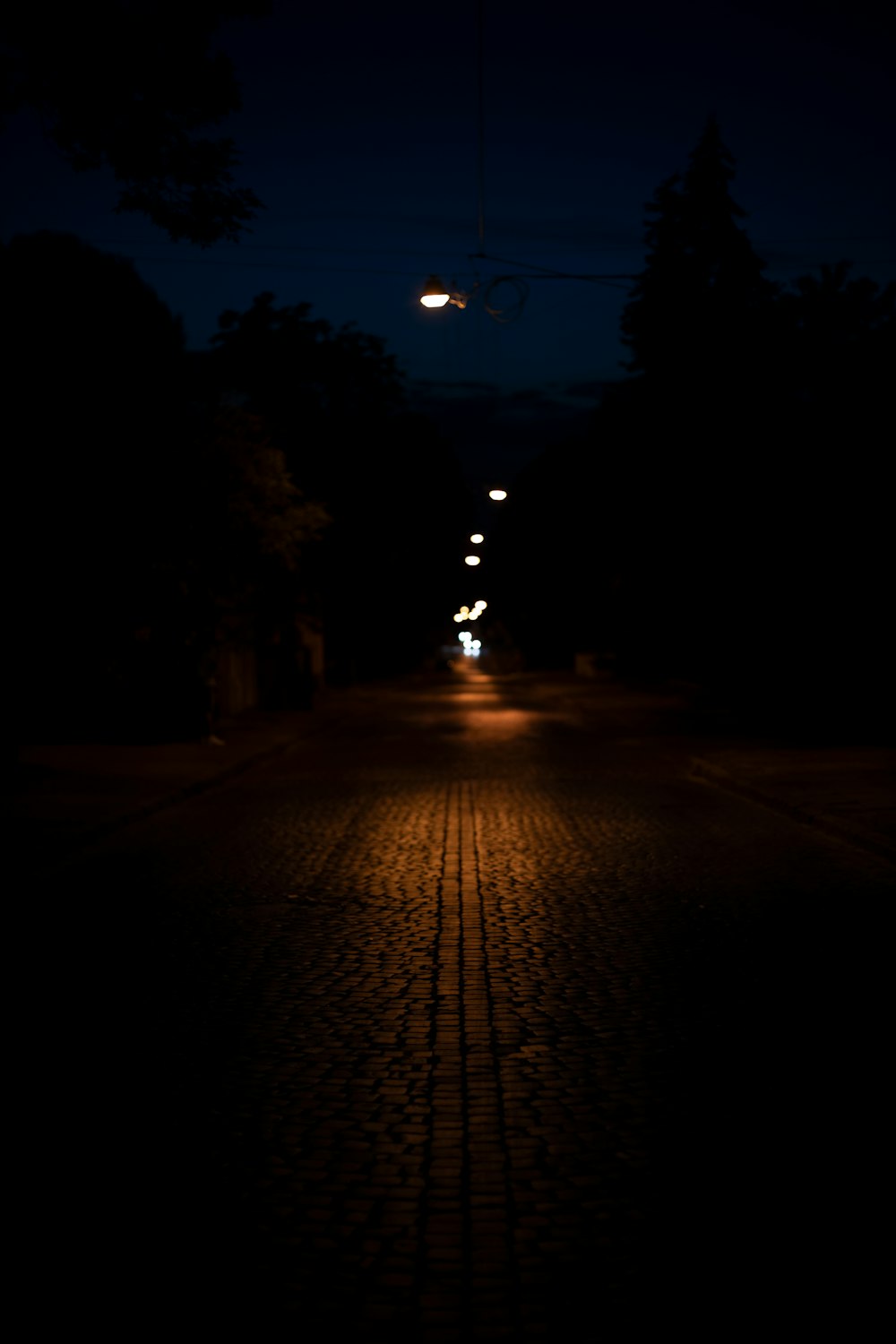 a street at night with a car driving down it