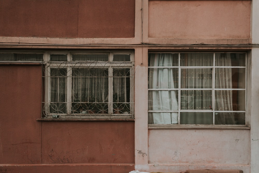 white framed glass window on red concrete building