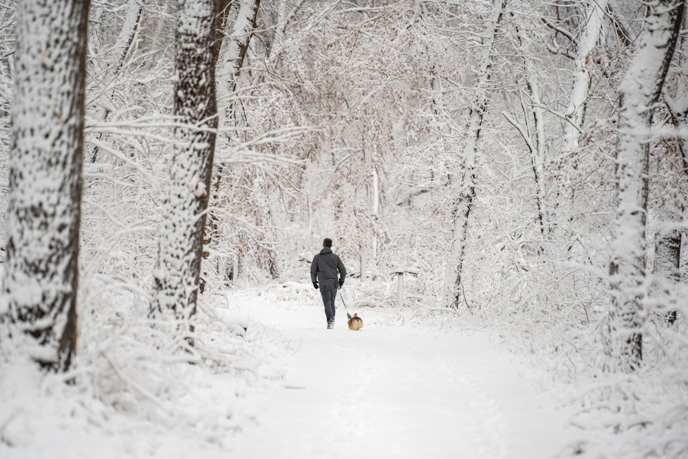 persona in giacca nera e pantaloni gialli che cammina su terreno coperto di neve durante il giorno