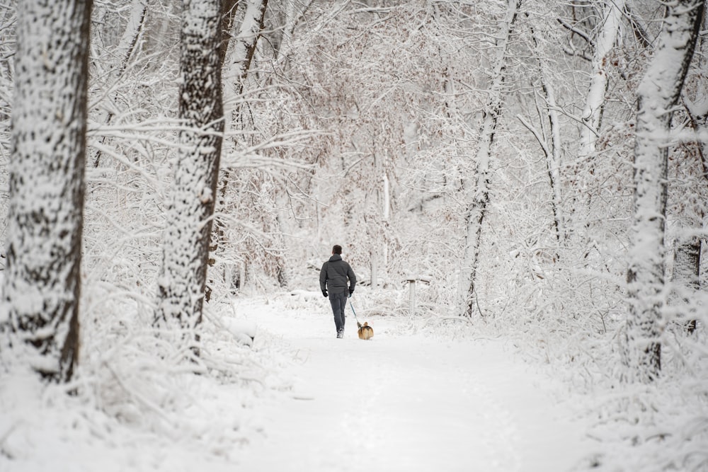 person in black jacket and yellow pants walking on snow covered ground during daytime