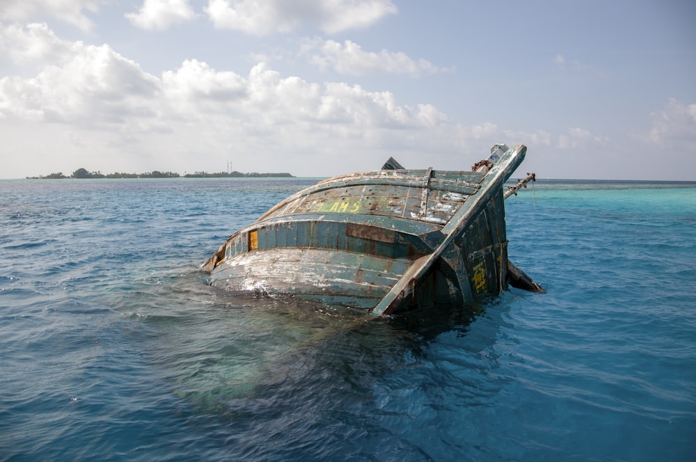 brown and green boat on sea under white clouds and blue sky during daytime