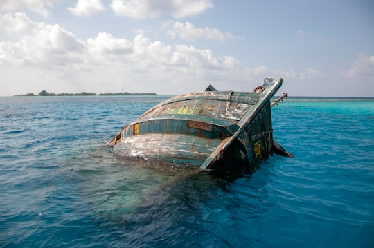 brown and green boat on sea under white clouds and blue sky during daytime in Keyodhoo Maldives