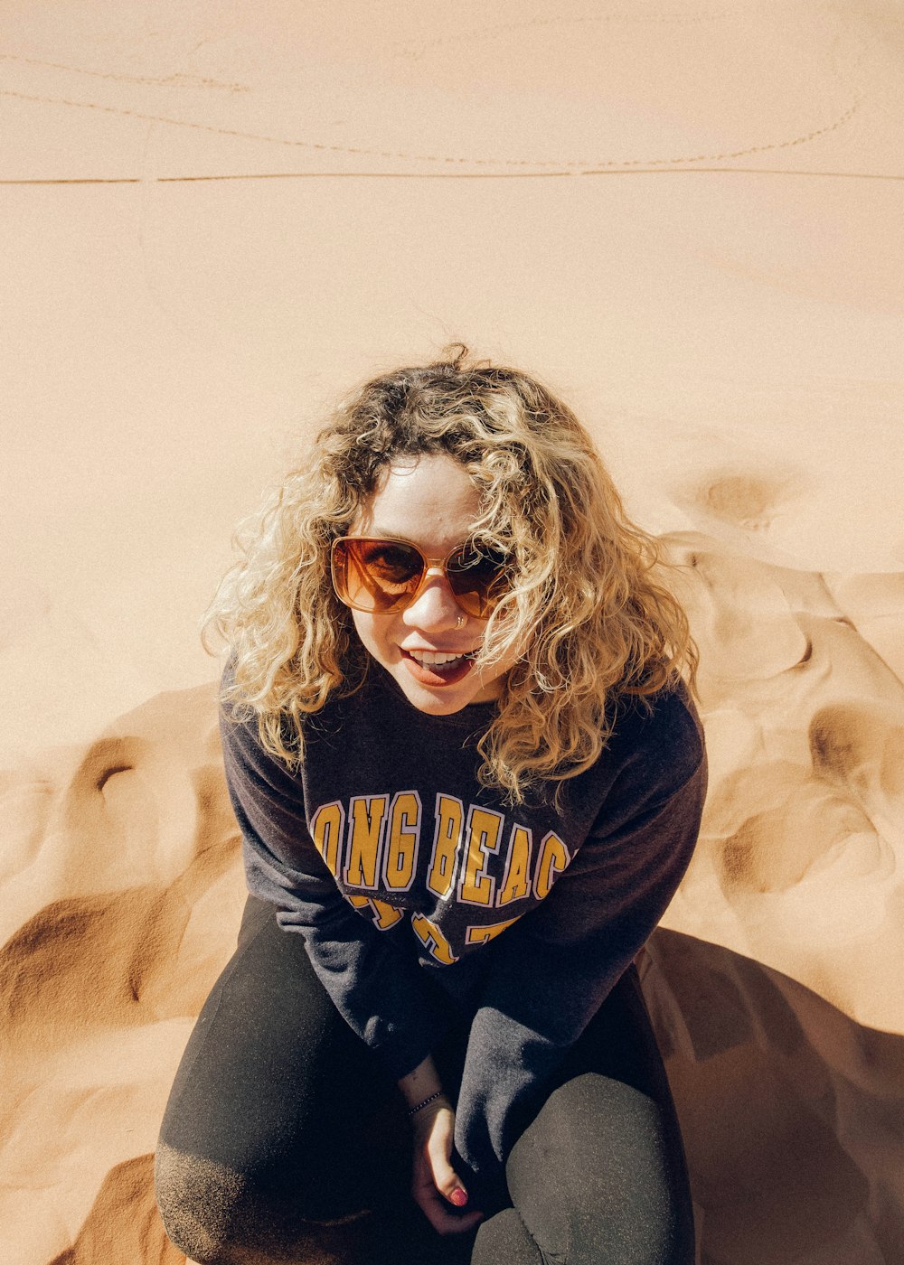 woman in black and brown long sleeve shirt wearing sunglasses sitting on white textile