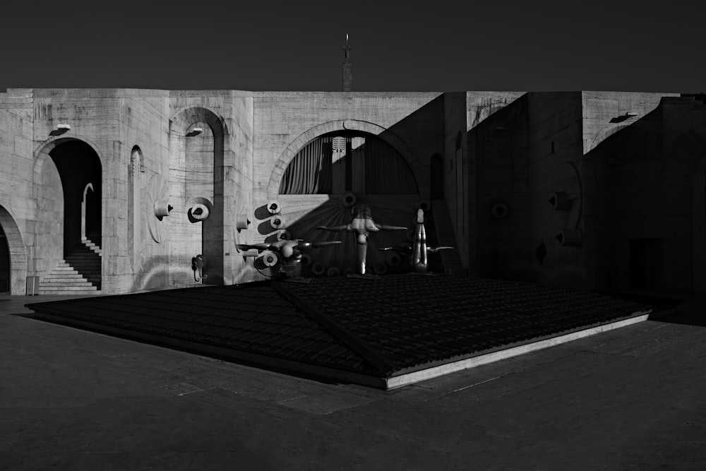 grayscale photo of people sitting on bench near building