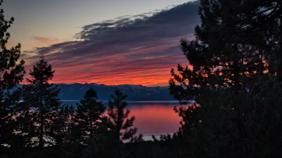 Sunset over a serene mountain lake with vibrant colors reflecting on the water.