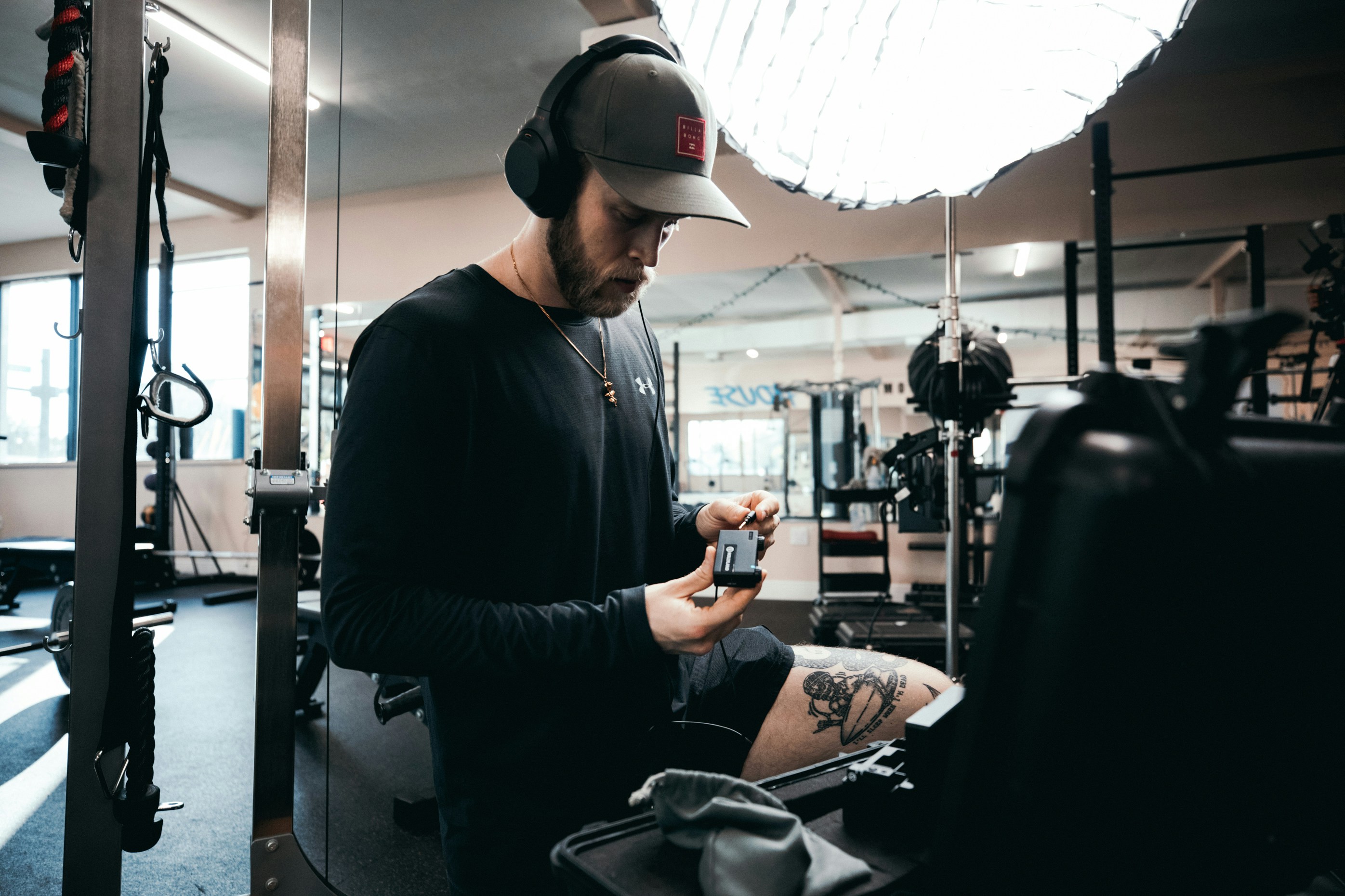 man in black long sleeve shirt and black cap holding smartphone