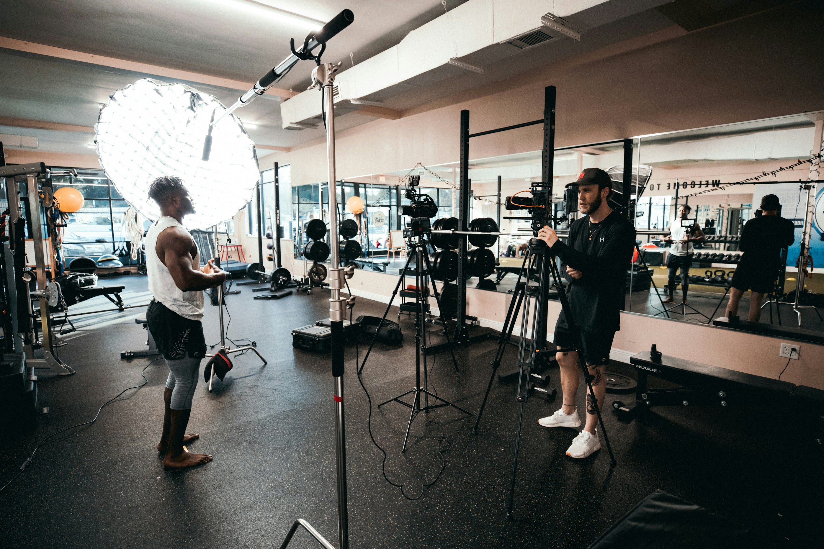 A fitness professional and crew films their video content, which will use royalty free music for workout videos.