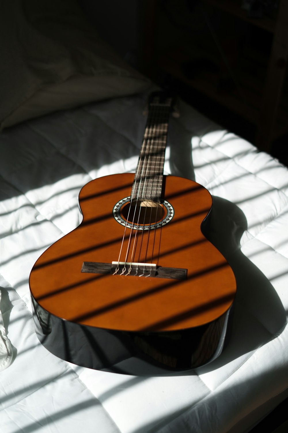 brown acoustic guitar on white textile