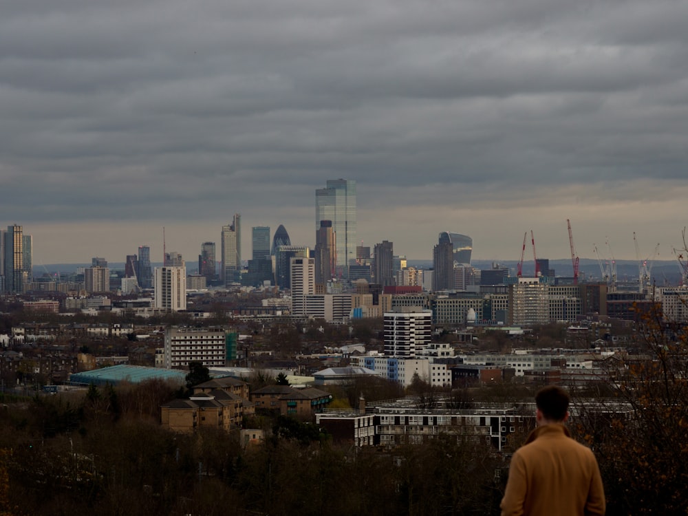 man in white shirt standing on top of building looking at city buildings during daytime