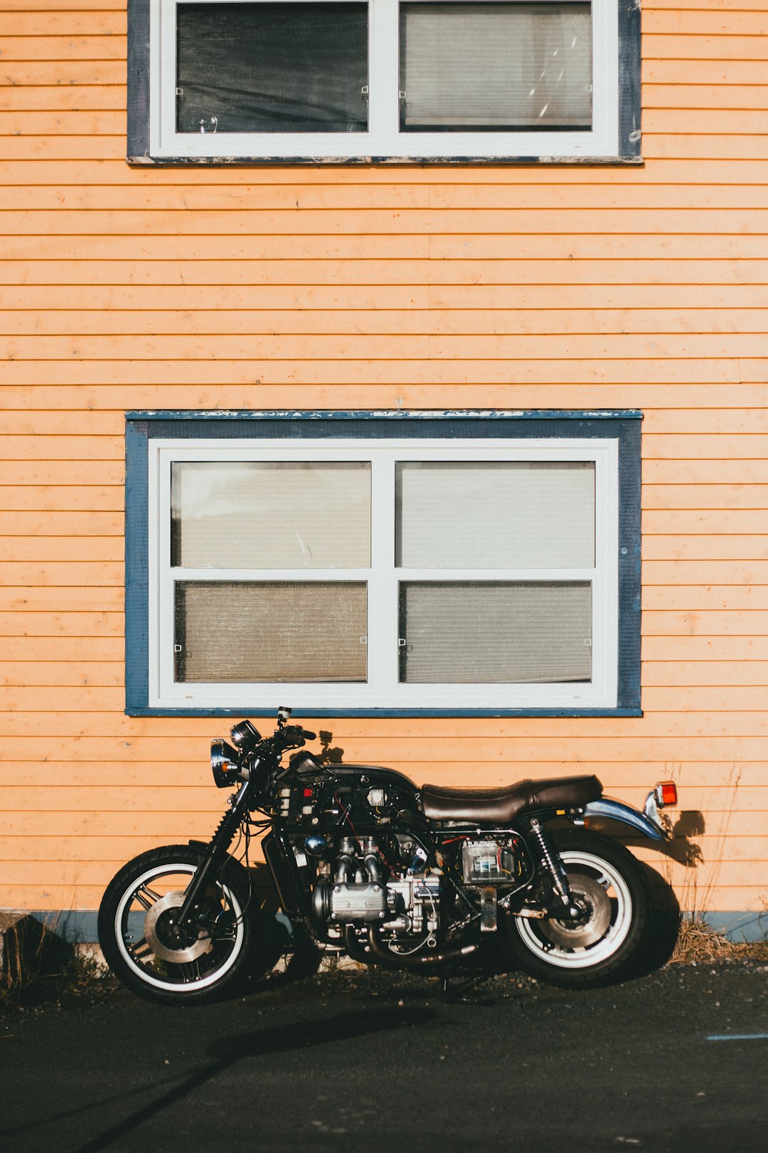 black cruiser motorcycle parked beside brown brick wall