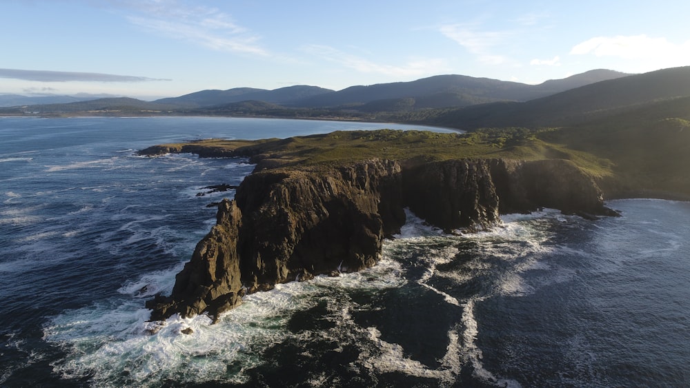 brown and green mountain beside body of water during daytime