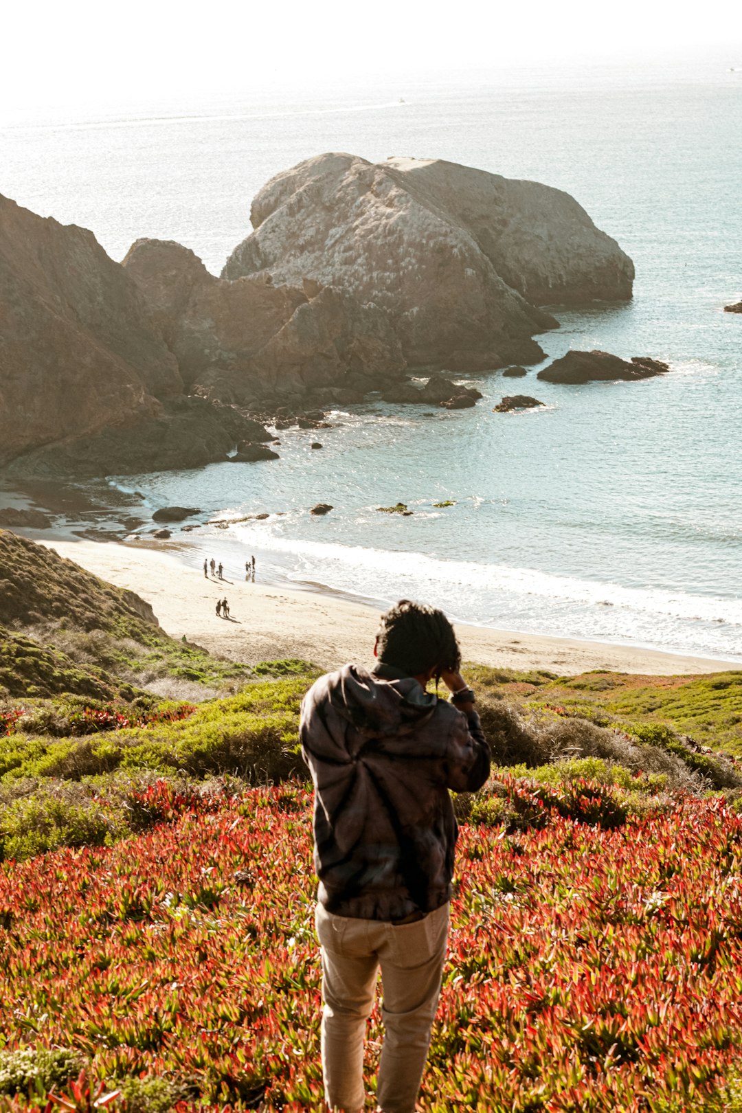 woman in brown coat standing on green grass field near body of water during daytime