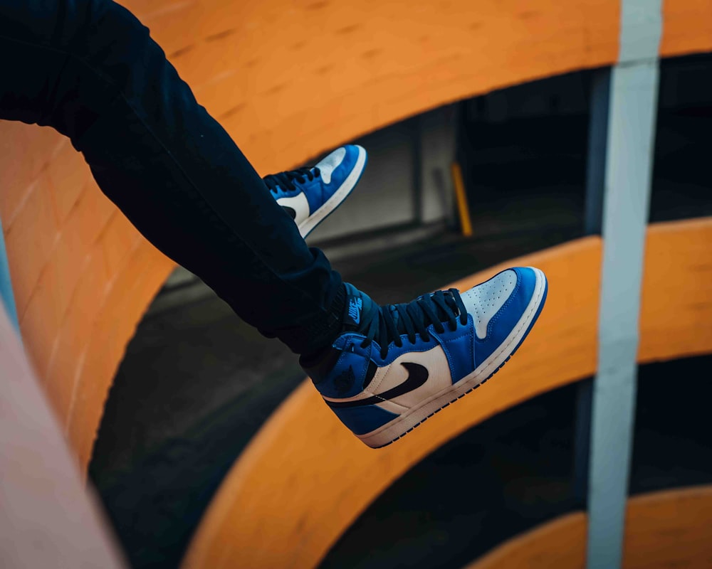 person in black pants wearing blue and white nike sneakers