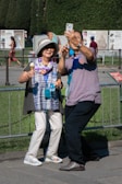 Couple taking a selfie at an open air photo booth with colorful props.
