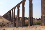 Wide shot of a completed aqueduct network with clear blue skies.