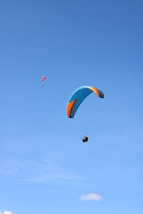person in red and yellow parachute in mid air during daytime
