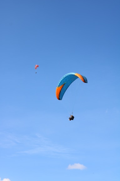 person in red and yellow parachute in mid air during daytime