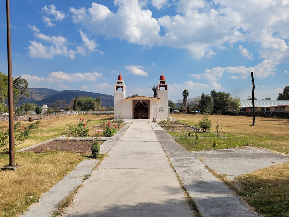 white concrete building near green grass field under blue sky and white clouds during daytime