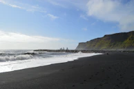 A rugged coastline with black sand beaches and crashing waves at Reynisfjara.
