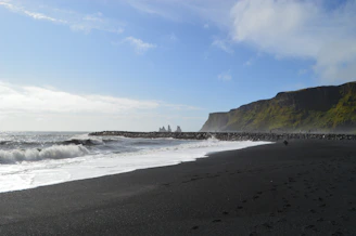 A rugged coastline with black sand beaches and crashing waves at Reynisfjara.