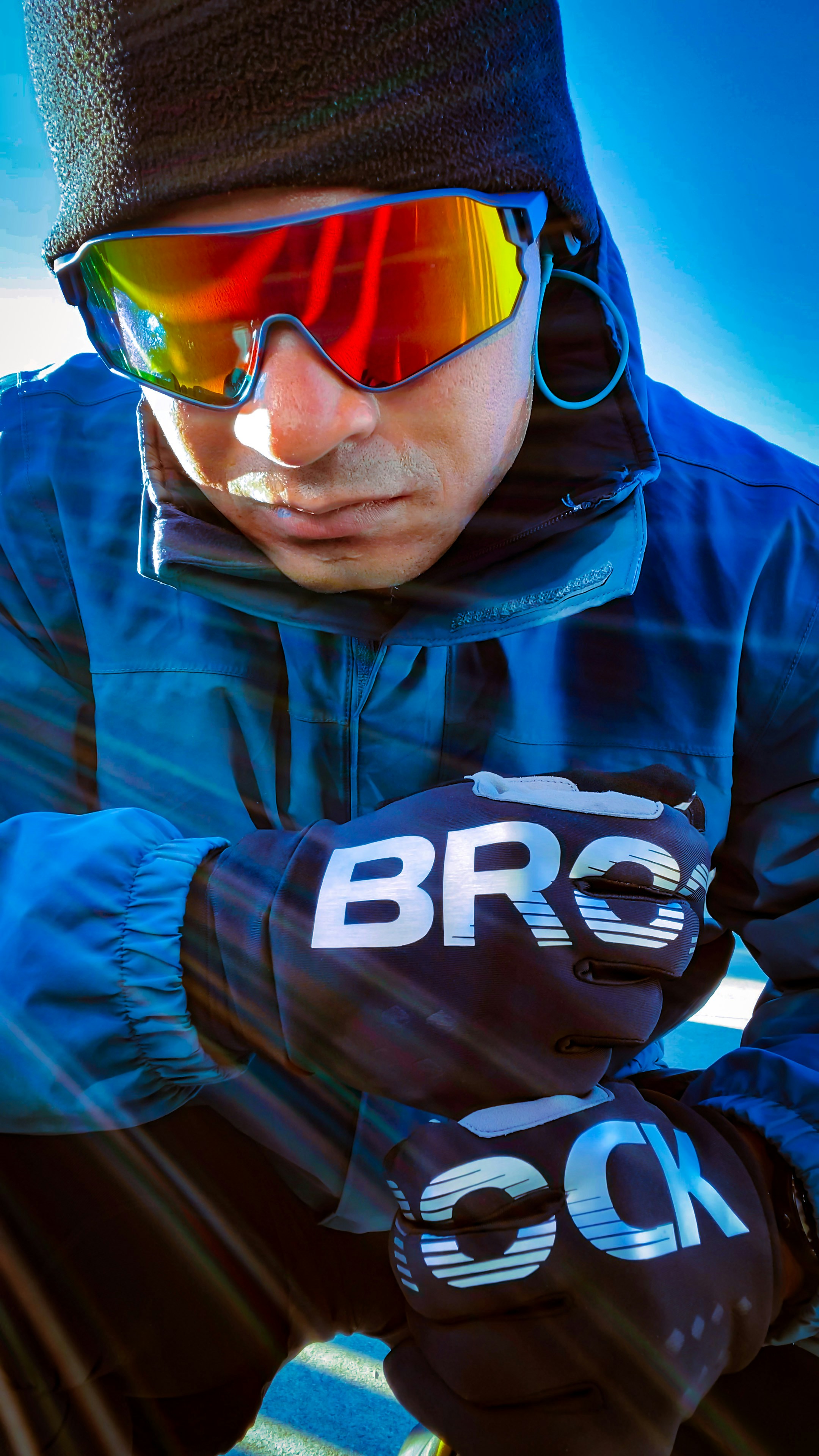 Man in a blue zip-up jacket wearing yellow-lens sport sunglasses