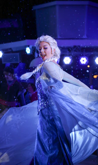 A graceful woman in a flowing, shimmering gown twirling under soft party lights.