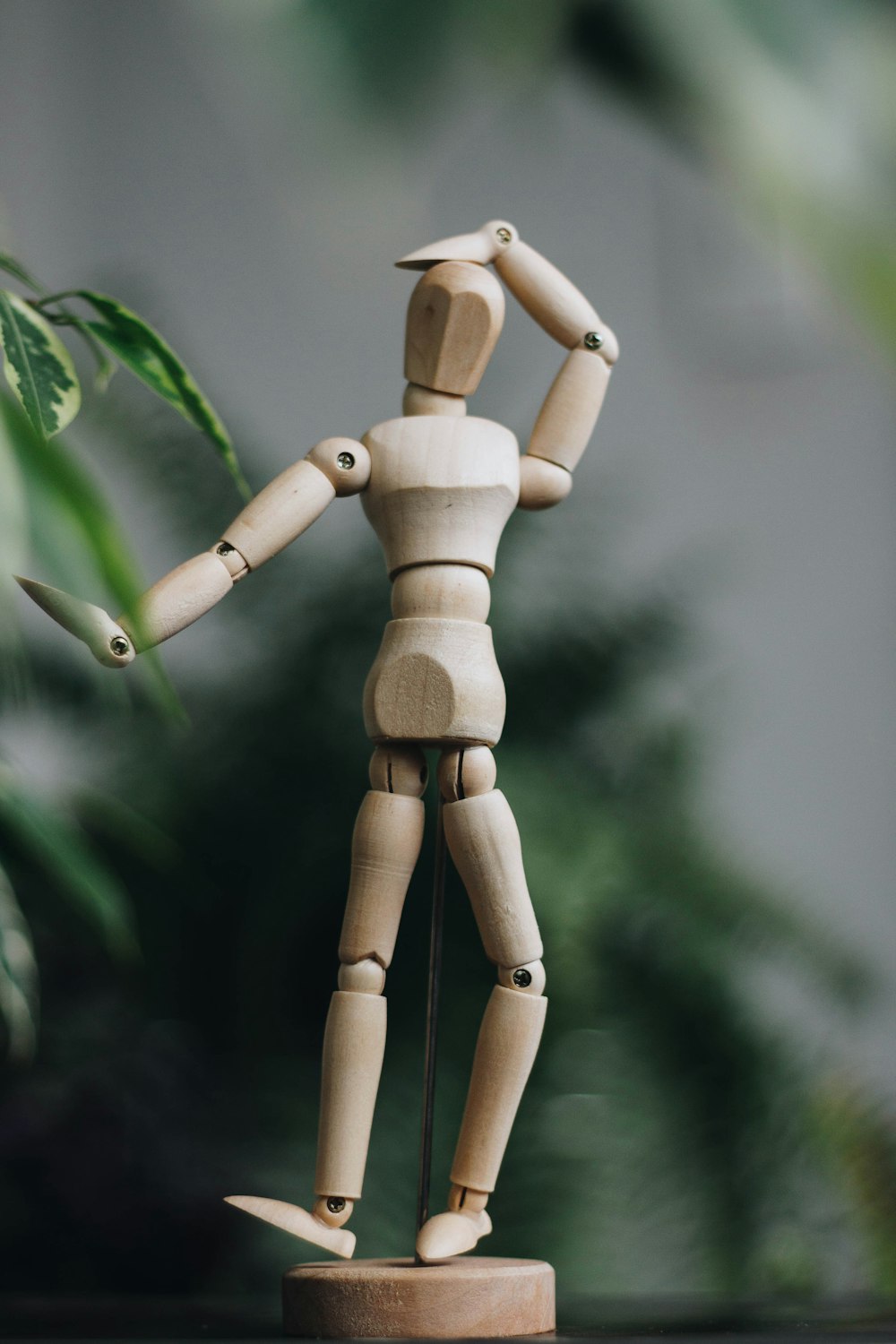 brown wooden human figure on green leaves