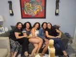 A group of diverse women smiling and supporting each other in a cozy room.