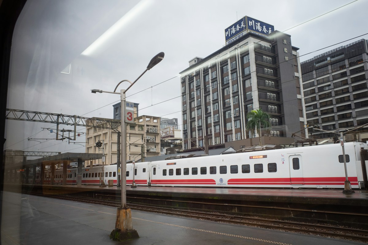 礁溪車站月台旁的列車，後方是溫泉區的飯店建築