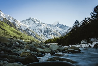 rocky river with snow covered mountains in the distance