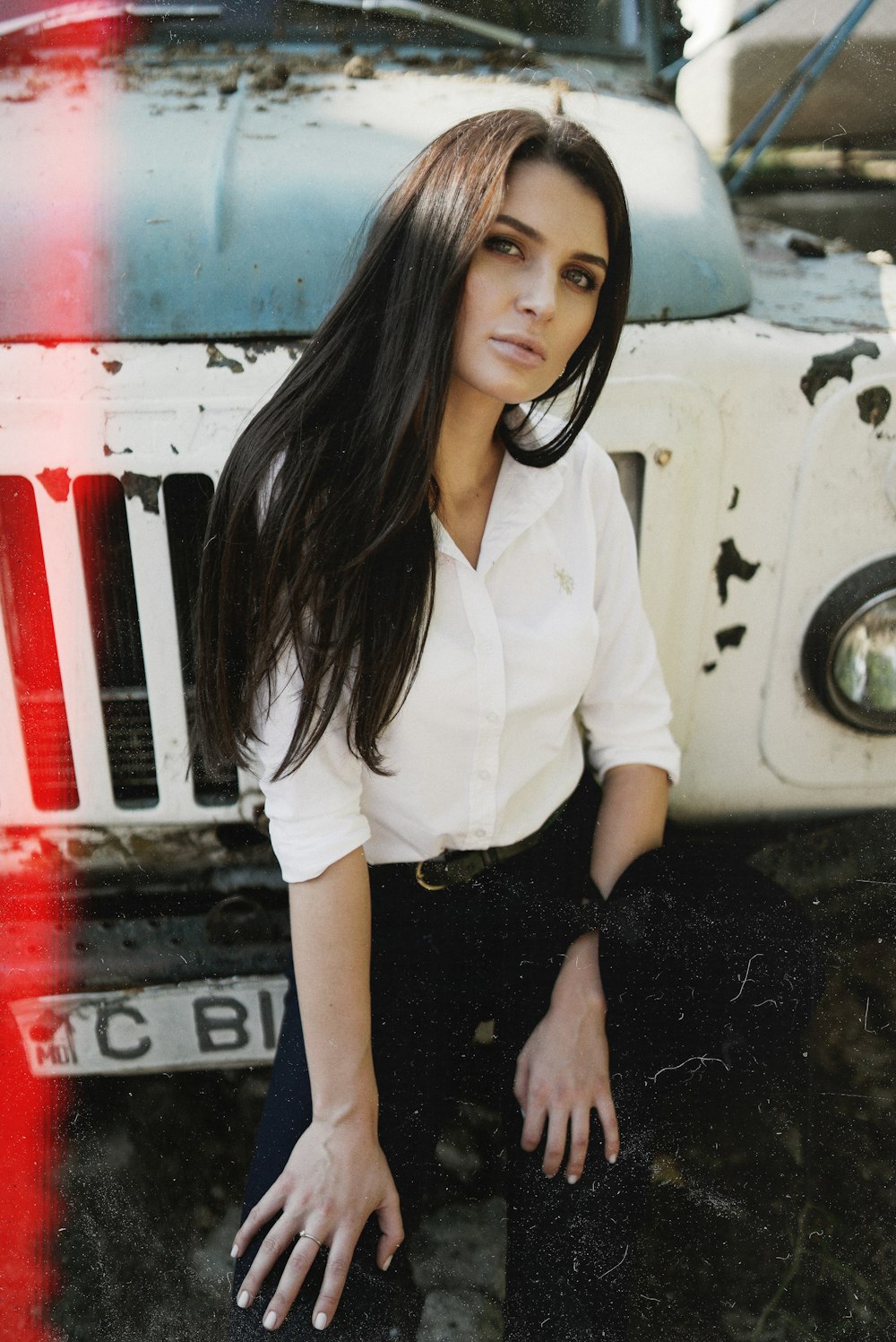 woman in white button up shirt and black skirt standing beside white car