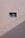 A simple beige wall with a small rectangular window, featuring a sliding design. The wall's texture appears rough and paint has subtle cracks. A shadow, likely from a utility line or similar object, diagonally crosses the bottom section of the image.