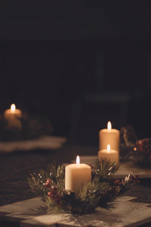 A cozy scene of glowing candles arranged on a rustic wooden table surrounded by seasonal decor.
