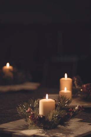 A cozy scene with several colorful candles arranged on a rustic table near a window.