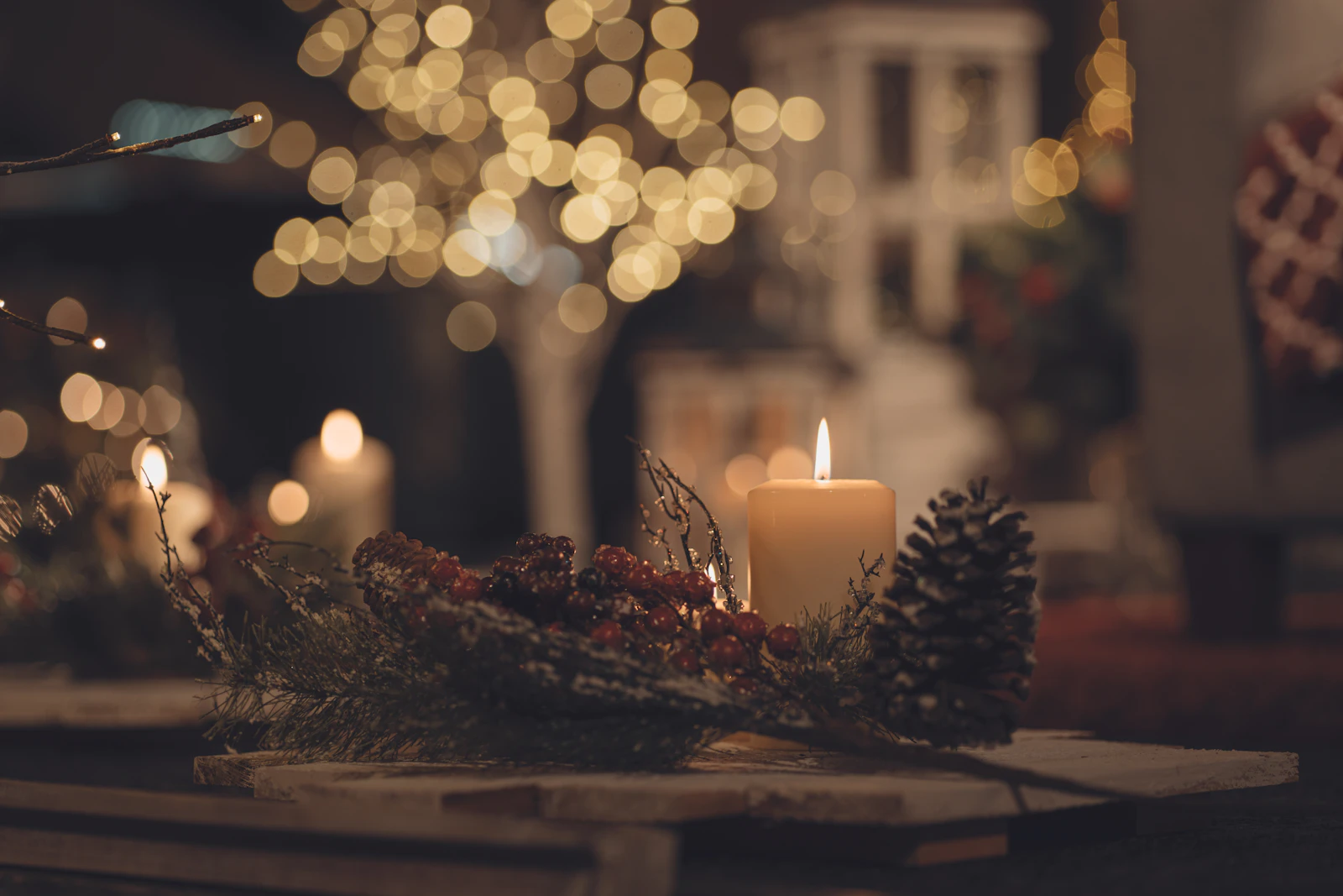 lit candles on a table with pine cones