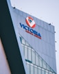A modern building facade with large glass windows, prominently displaying signage for a medical center in bold blue and red colors against a sleek grey exterior.