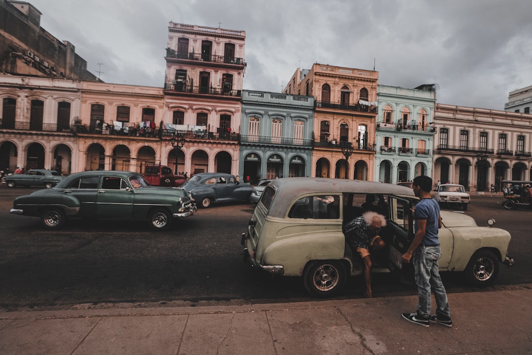 man in blue shirt standing beside white car during daytime