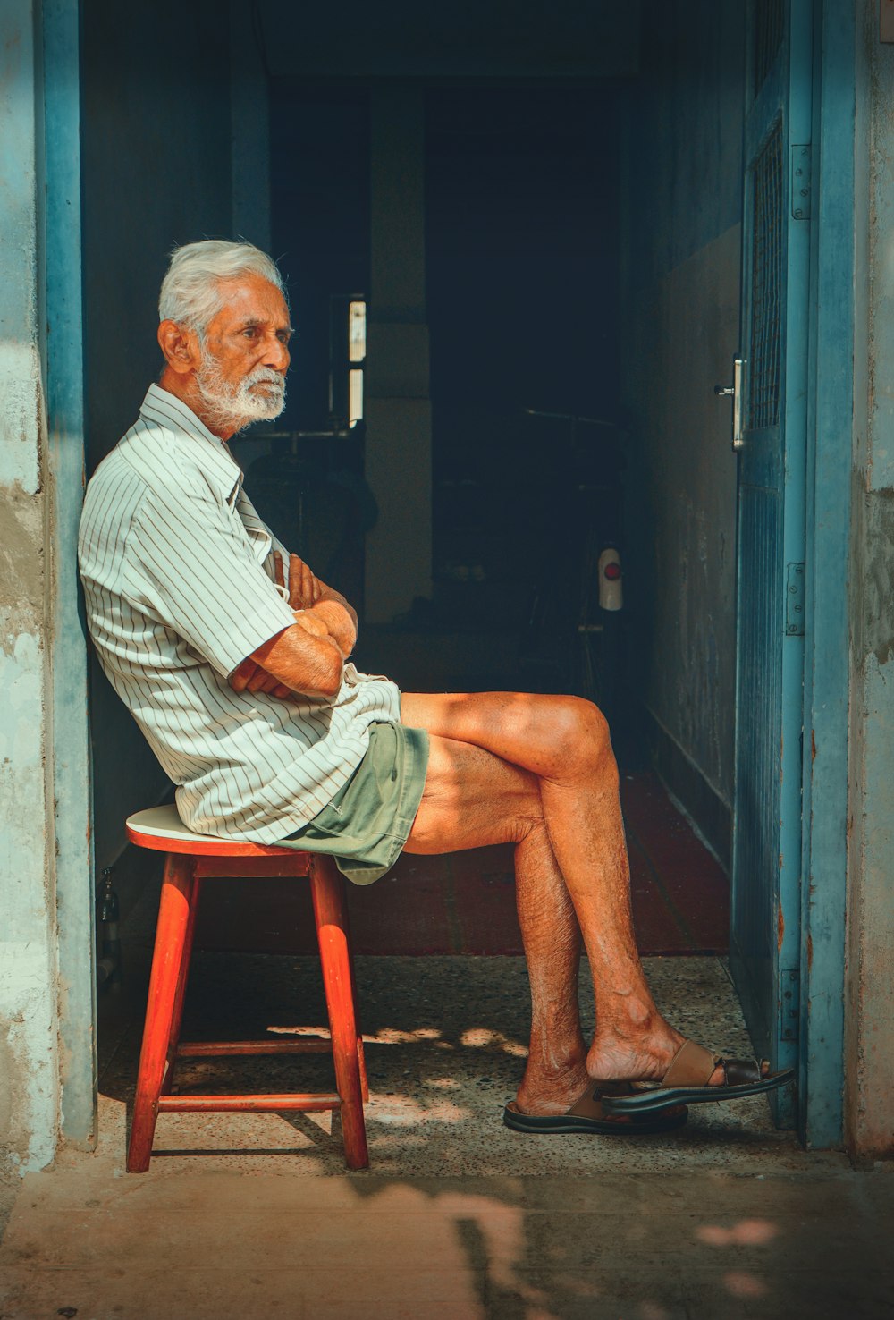 man in white and black stripe dress shirt sitting on brown wooden chair