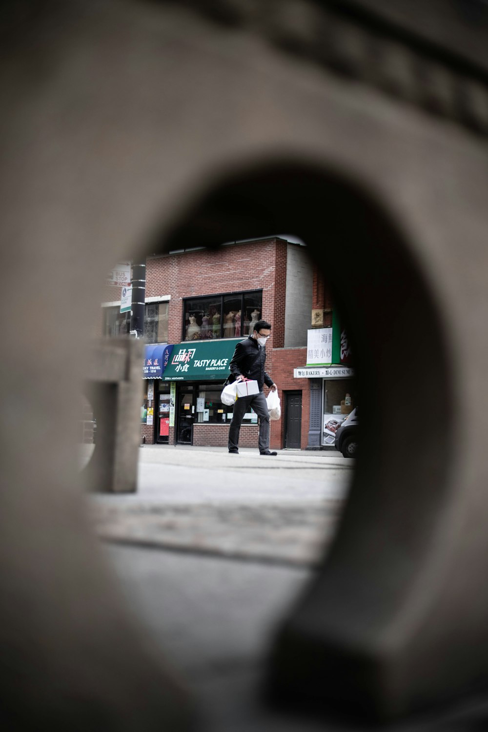 man in black jacket and black pants walking on sidewalk during daytime