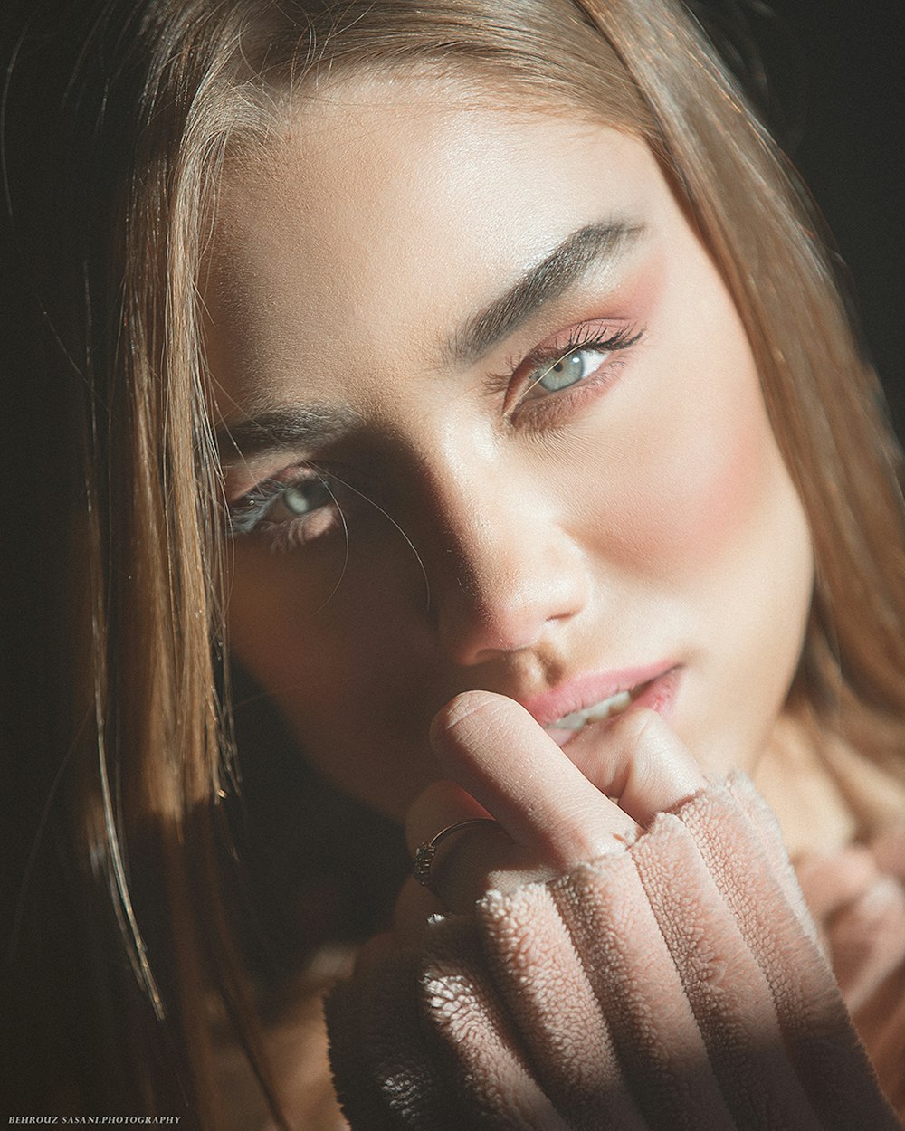 woman with brown hair covering her mouth