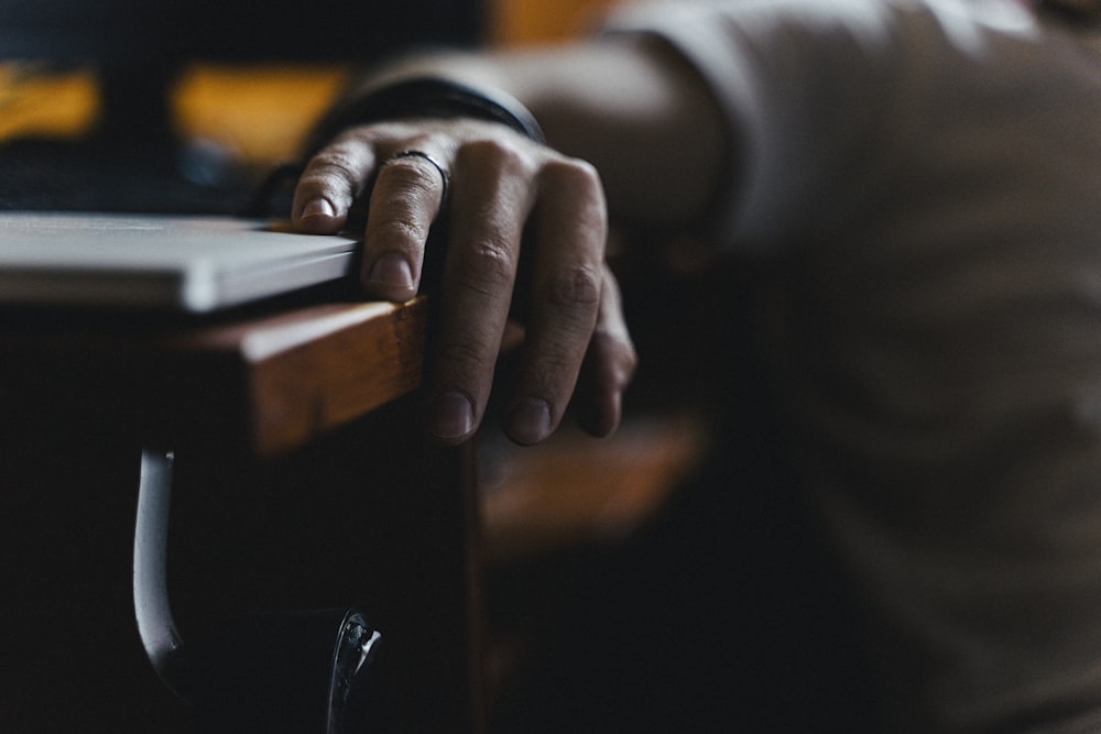 person in black long sleeve shirt holding brown wooden table